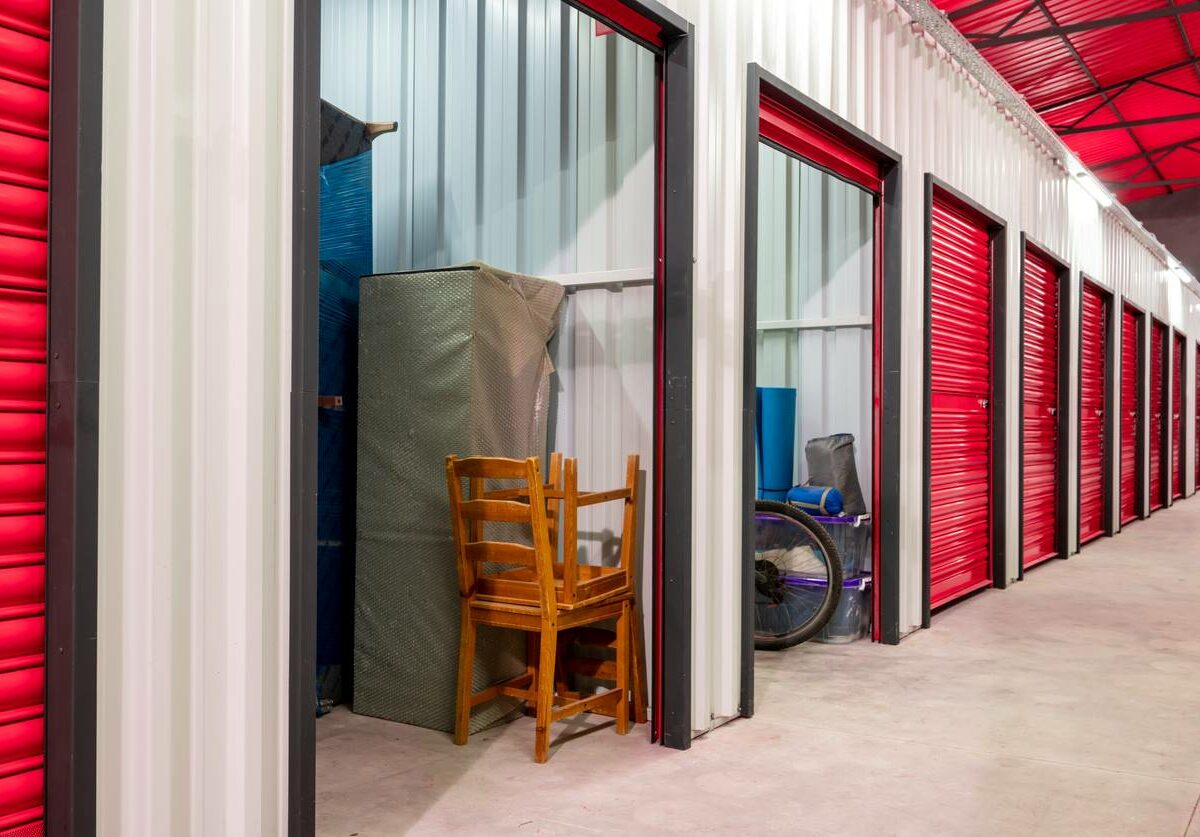 A row of red-doored self storage lockers inside a self storage facility.