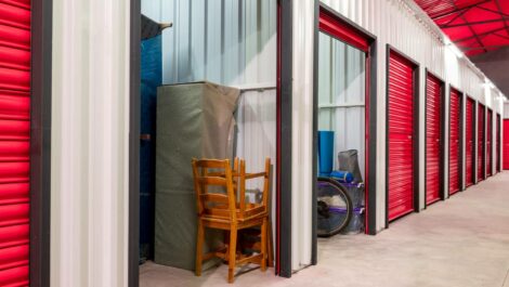 A row of red-doored self storage lockers inside a self storage facility.
