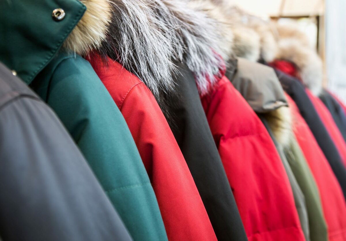 An assortment of winter and down jackets on hangers in a row.