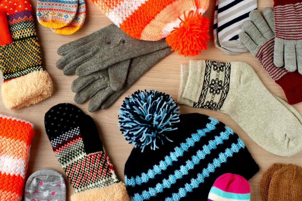 An assortment of caps, mittens, gloves, and socks from the top view for cold seasons.