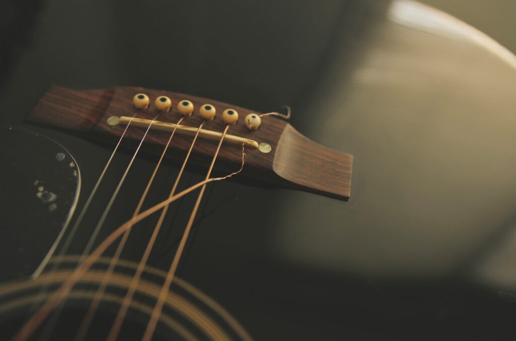 A black acoustic guitar with a string broken by exposure to extreme temperatures.