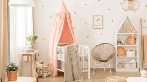 A nursery with a crib, bookshelf, toys, and blankets.