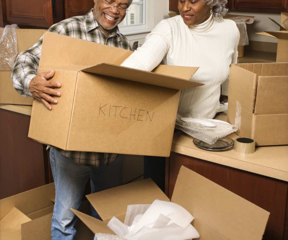 A mature, senior couple packing boxes in their kitchen in preparation to move.