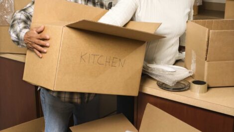A mature, senior couple packing boxes in their kitchen in preparation to move.