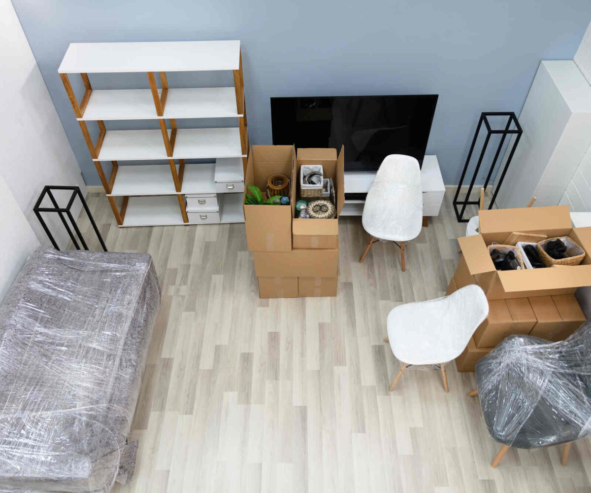 A living room with furniture being wrapped and packed up in preparation to go into storage.