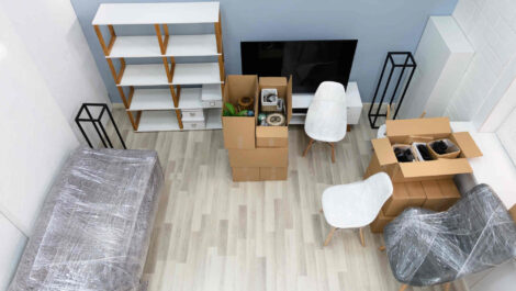 A living room with furniture being wrapped and packed up in preparation to go into storage.