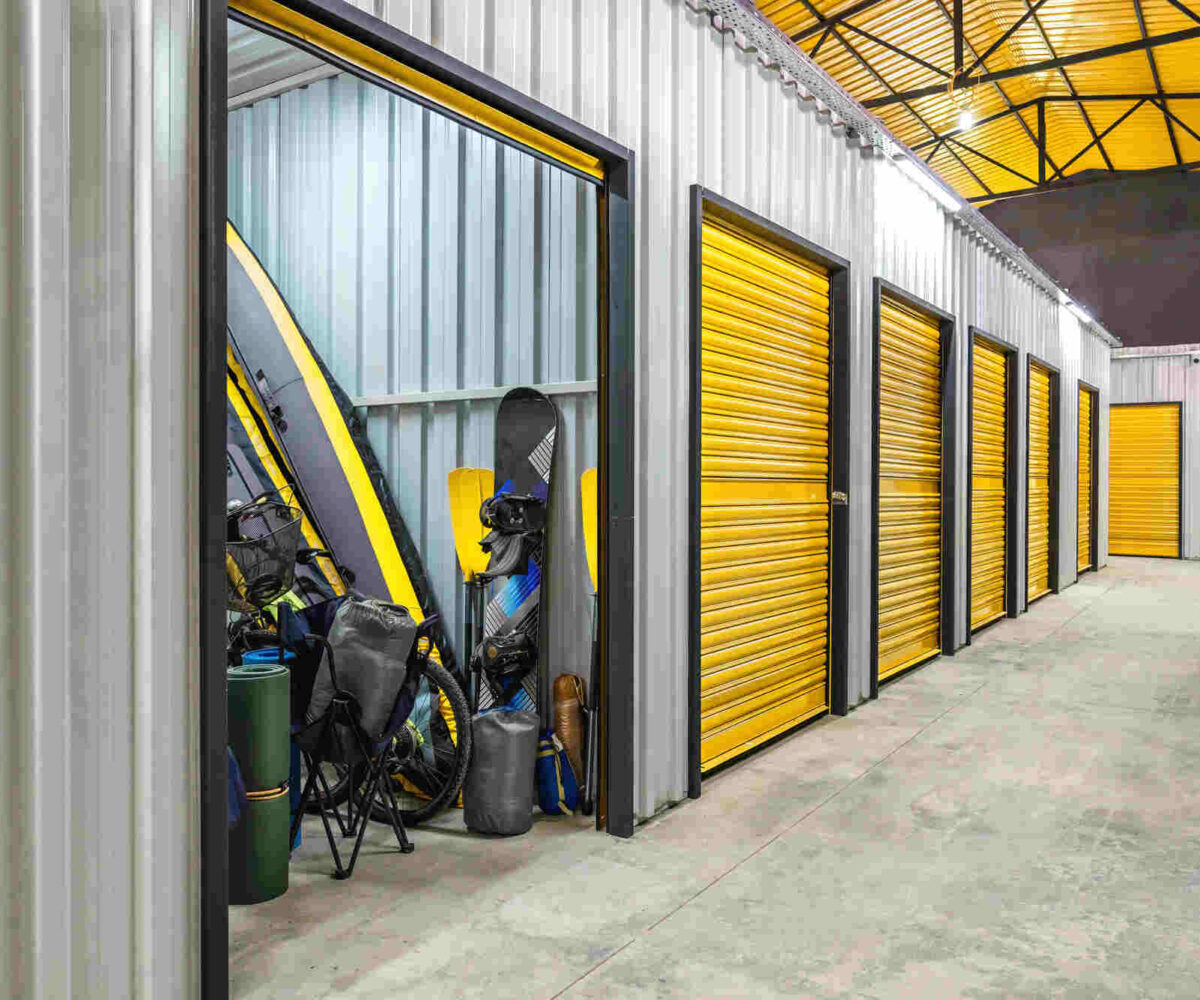 A storage unit filled with seasonal sporting goods, such as a kayak and snowboard.