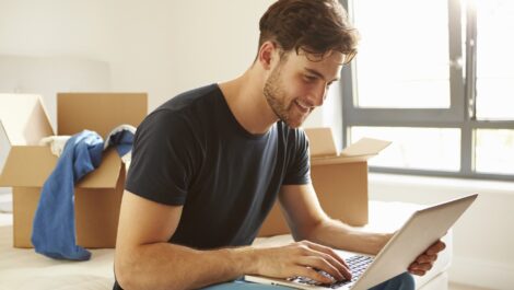 A person packing up boxes to move pauses briefly to do some work on a laptop.